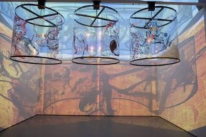 Gamepieces. 2003/2009. Installation. Four-channel video/shadow play (color, sound, 12 min.) and synthetic polymer paint on six Lexan cylinders. Image, courtesy the artist. Link: https://www.youtube.com/watch?v=gCVS9FlT0Hs